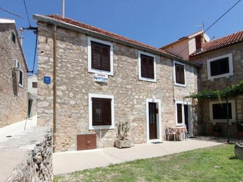 a large stone building with black shutters on it at Apartments Matej in Bol
