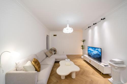 a white living room with a couch and a tv at Shanghai Hills & Serendipity Springtime Family BNB with Two Rooms close to West Nanjing Rd in Shanghai