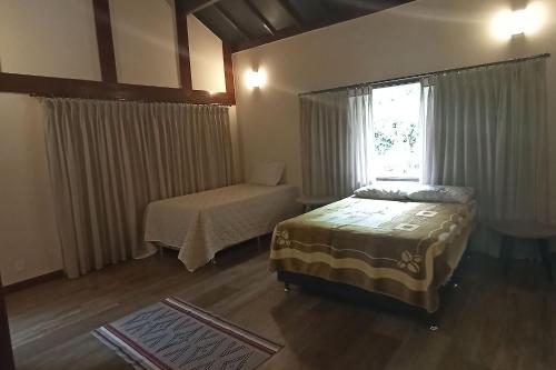 a bedroom with two beds and a window at Gaia Hotelaria in Teresópolis