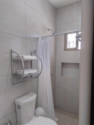 a white bathroom with a shower and a toilet at Departamentos X`Kanlol in Izamal