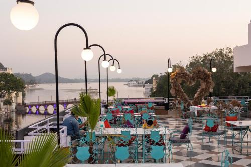 a patio with tables and chairs with a view of the water at Hide-In Udaipur - A Lake View Boutique Hotel in Udaipur