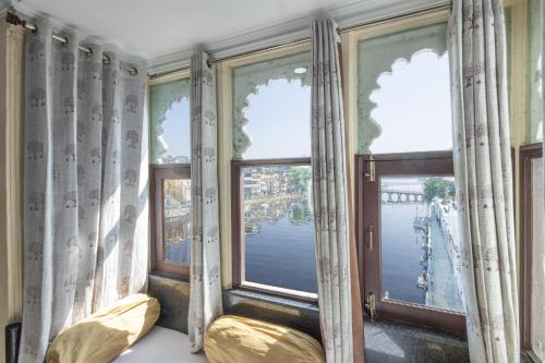 a room with windows with a view of the water at Hide-In Udaipur - A Lake View Boutique Hotel in Udaipur