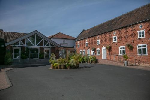 a group of brick buildings with plants in a courtyard at The Telford Hotel, Spa & Golf Resort in Telford