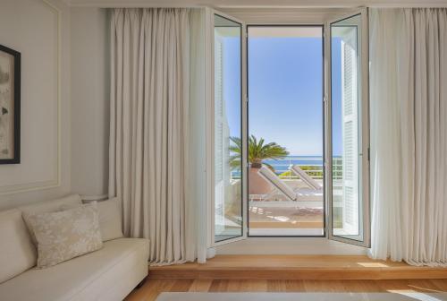 a living room with a large window with a view of the ocean at Grand-Hôtel du Cap-Ferrat, A Four Seasons Hotel in Saint-Jean-Cap-Ferrat