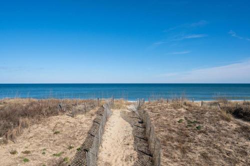 a fence on a sandy beach near the ocean at OBX 4BR Oceanfront Cottage in Kill Devil Hills
