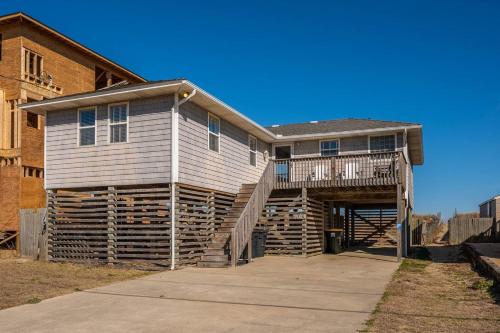 a house with a wooden staircase leading up to it at OBX 4BR Oceanfront Cottage in Kill Devil Hills