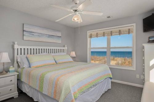 a bedroom with a bed and a window with the ocean at OBX 4BR Oceanfront Cottage in Kill Devil Hills