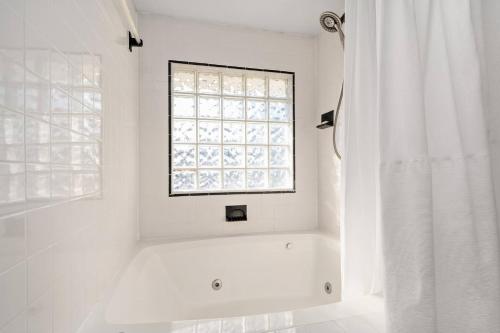 a white bathroom with a window and a bath tub at OBX 4BR Oceanfront Cottage in Kill Devil Hills