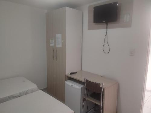 Habitación pequeña con cama y escritorio con TV. en Melquiades Hotel, en Patos