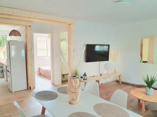 un soggiorno bianco con tavolo e TV di Cosy a Canet-en-Roussillon