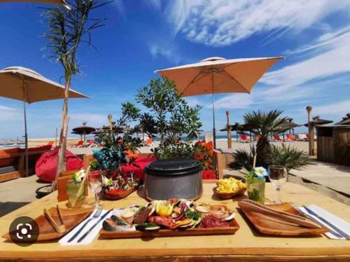un tavolo con cibo sopra con la spiaggia sullo sfondo di Cosy a Canet-en-Roussillon