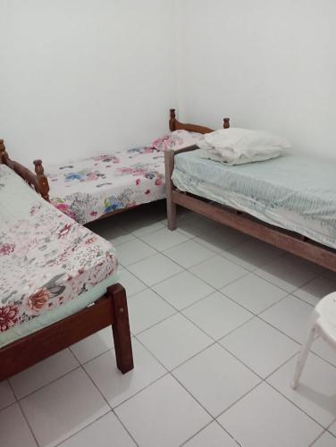 three beds in a room with a white tiled floor at Casa pousada Milton in Angra dos Reis