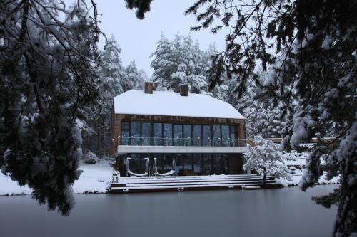 a building covered in snow next to a body of water at Kernavės Pajauta in Kernavė