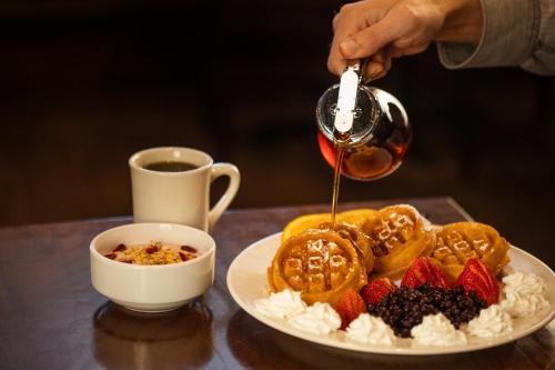 a person is pouring syrup onto a plate of food at Holiday Inn West Yellowstone by IHG in West Yellowstone
