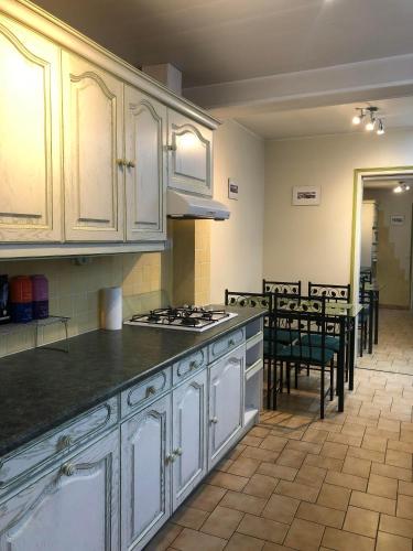 une cuisine avec des armoires blanches et une table avec des chaises dans l'établissement Maison arrageoise authentique, entre ville et parc, à Arras