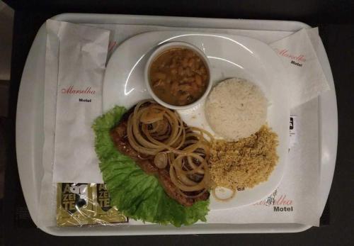 un plato de comida con arroz, carne y lechuga en Vem Para o - Motel Marselha 2, en São Paulo