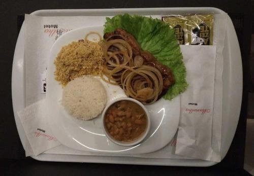 a plate of food with rice and meat and beans at Vem Para o - Motel Marselha 3 in Sao Paulo