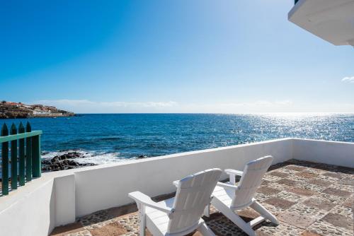 two chairs sitting on a balcony overlooking the ocean at Traditional Canary beach house in Poris de Abona