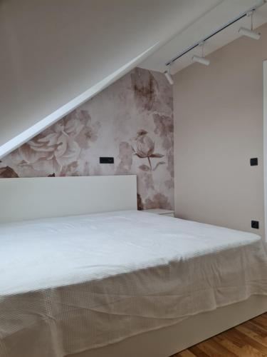ズラティボールにあるZlatibor Zlatni danの白いベッドと花の壁が備わるベッドルーム1室が備わります。
