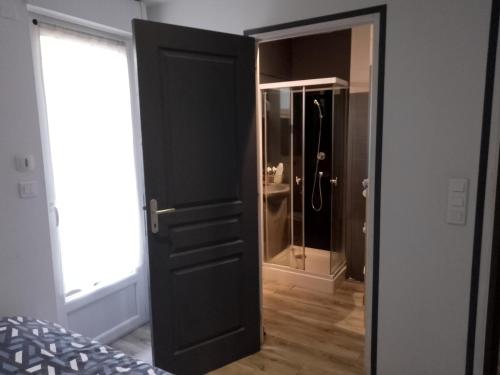 a black door leading to a bathroom with a shower at Un Appartement tout à vous in Carhaix-Plouguer