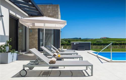 a row of lounge chairs with an umbrella and a pool at Villa Luna in Brtonigla