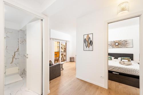 Cette chambre blanche comprend un lit et un miroir. dans l'établissement Castel - Agréable deux pièces - Centre Menton, à Menton