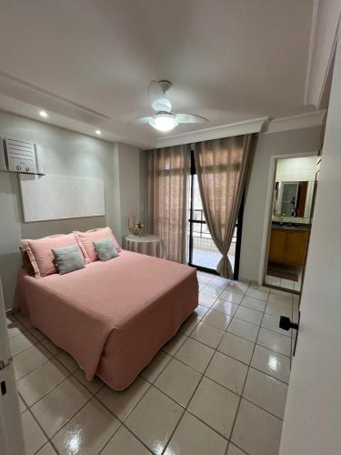 a bedroom with a pink bed with pink pillows at O PARAÍSO É AQUI! Apto muito próximo a praia in Guarapari