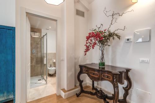 a bathroom with a table with a vase of flowers on it at Suite della Pigna in Rome