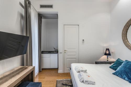 a white bedroom with a bed and a television at Suite della Pigna in Rome