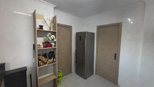 a kitchen with a refrigerator and a door and shelves at Rural El Bosque in Entrambasaguas
