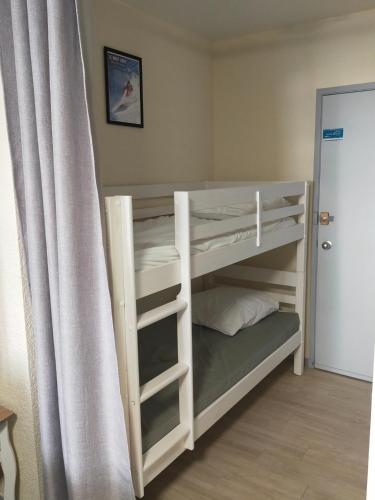 Ce lit superposé se trouve dans une chambre à côté d'un rideau. dans l'établissement Studio 2 - Mont Dore face aux Thermes - Hyper-Centre, à Le Mont-Dore