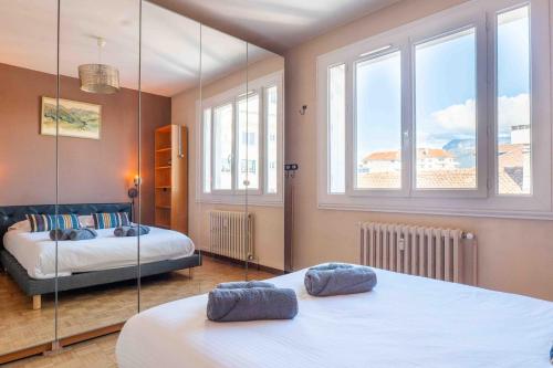 une chambre avec deux lits et deux fenêtres dans l'établissement Le Sommeiller, à Annecy