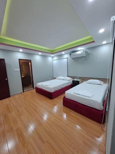 two beds in a room with a wooden floor at Hotel Family Inn in Dhaka