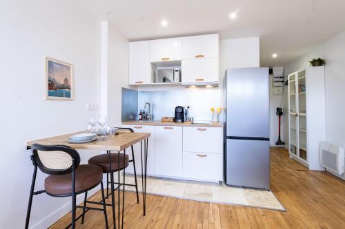 une cuisine avec une table et un réfrigérateur dans l'établissement Prestige by Opera - Votre évasion cosy à Toulouse - Centre ville - Wifi - Bureau, à Toulouse