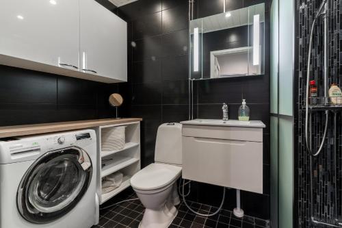 a bathroom with a toilet and a washing machine at Cozy and modern apartment with lakeside view in Rovaniemi