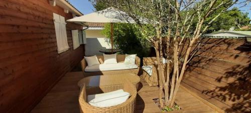 un patio avec une table, des chaises et un parasol dans l'établissement Hourtin Charmant Chalet avec Salon de Jardin, à Hourtin