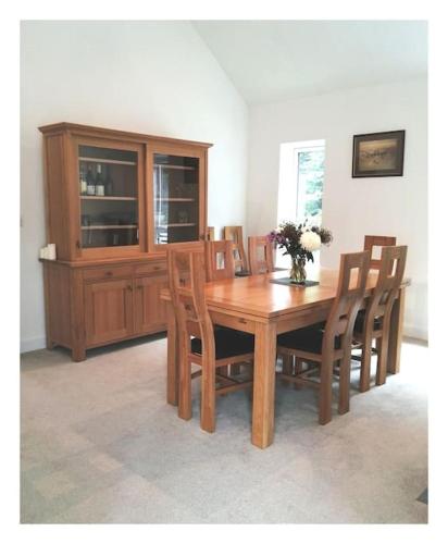a wooden dining room table with chairs and a cabinet at The Highlands - 5 bed 5 bath - Huge Sociable House in Exning