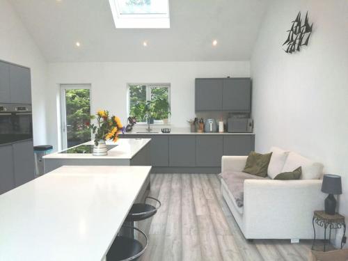 a white living room with a couch and a kitchen at The Highlands - 5 bed 5 bath - Huge Sociable House in Exning