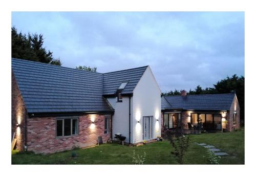 a white home with a black roof at The Highlands - 5 bed 5 bath - Huge Sociable House in Exning
