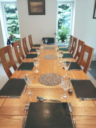 a long wooden table with wine glasses on it at The Highlands - 5 bed 5 bath - Huge Sociable House in Exning