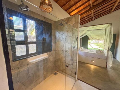Un baño con ducha y una cama en una habitación. en Villa Flora, en Amontada
