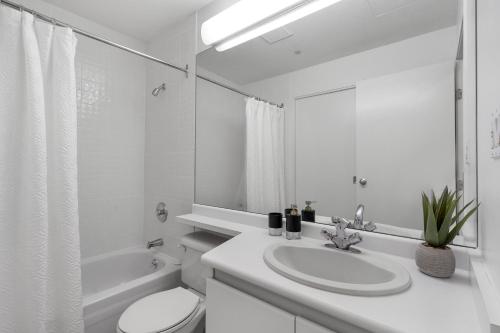 a white bathroom with a sink and a toilet at Central Downtown Highrise Condo in Vancouver