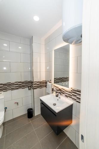 a white bathroom with a sink and a mirror at Sea Breeze, Spacious 2-Bedroom LUX Seaside Apartments in St. Paul's Bay