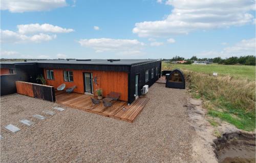 a small house with a wooden deck next to a field at Awesome Home In Thisted With Sauna in Thisted