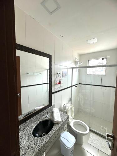 a bathroom with a sink and a toilet and a mirror at Sophia I - Praia Grande in Arraial do Cabo