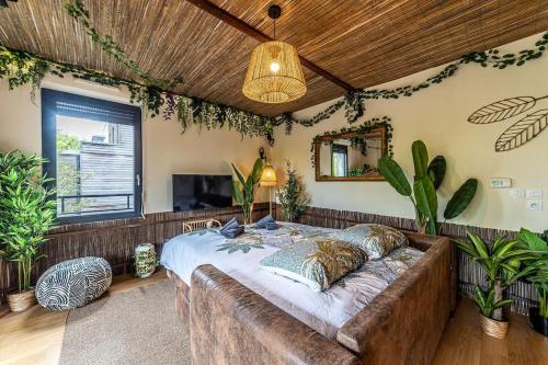 - un grand lit dans une chambre ornée de plantes dans l'établissement Le Repaire de Simba - Near DIsneyland Paris, à Montévrain