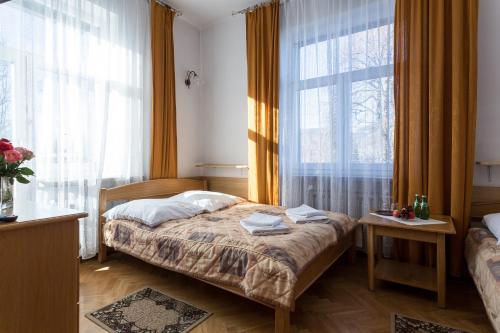 a small bedroom with a bed and two windows at Pensjonat Adria in Zakopane