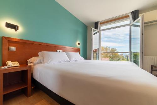 ein Schlafzimmer mit einem großen weißen Bett und einem Fenster in der Unterkunft Hotel Playa Langosteira by Adeloló in Kap Finisterre
