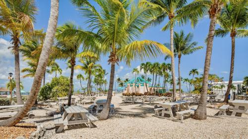 a sandy beach with palm trees and picnic tables at Mermaid Magic by Last Key Realty in Cudjoe Key