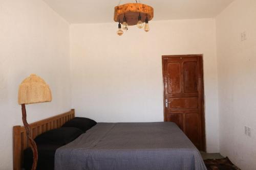a bedroom with a bed and a lamp and a door at Chale com vista e acesso ao Rio Grande - MG in Delfinópolis
